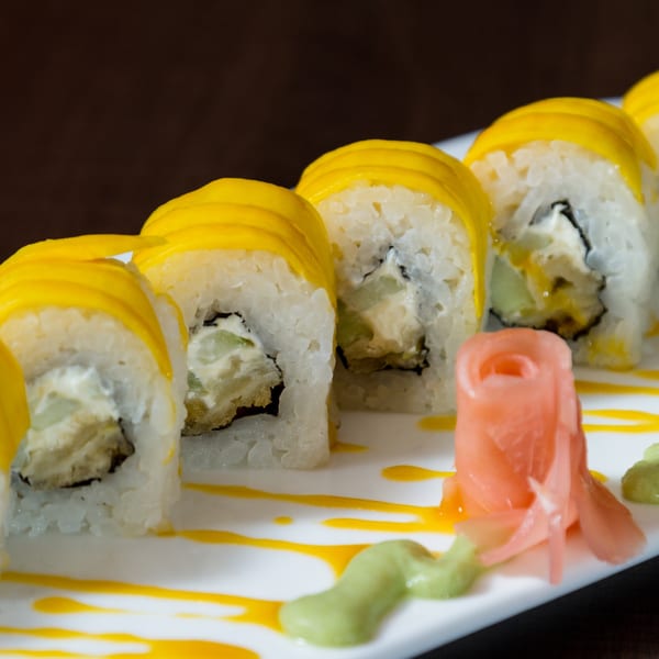 Crab Fever's mango sushi rolls with ginger and wasabi on a white plate.